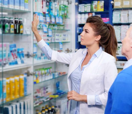 Beautiful young woman pharmacist showing drugs to senior man customer in pharmacy.